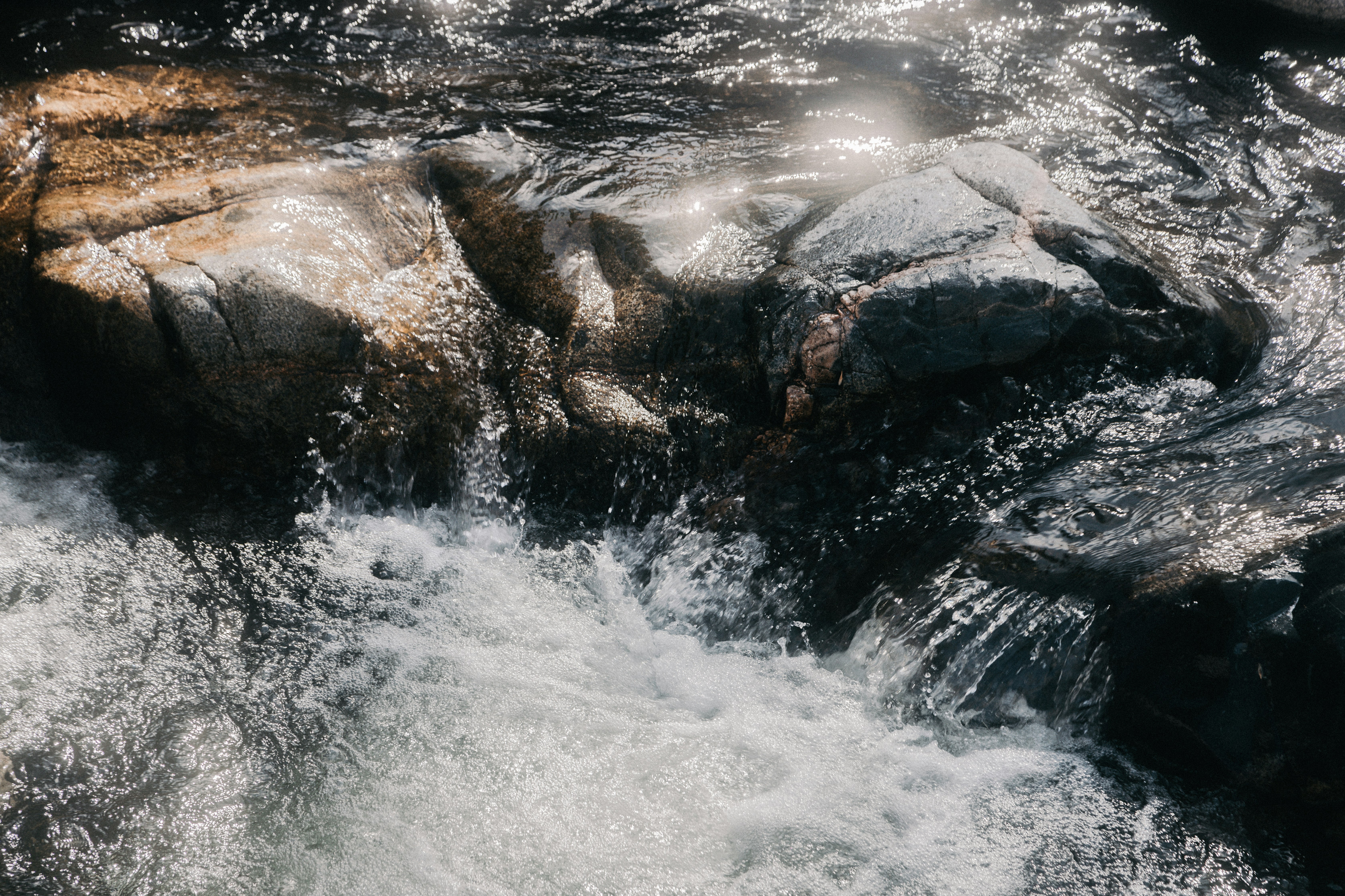 water falls on rocky shore during daytime